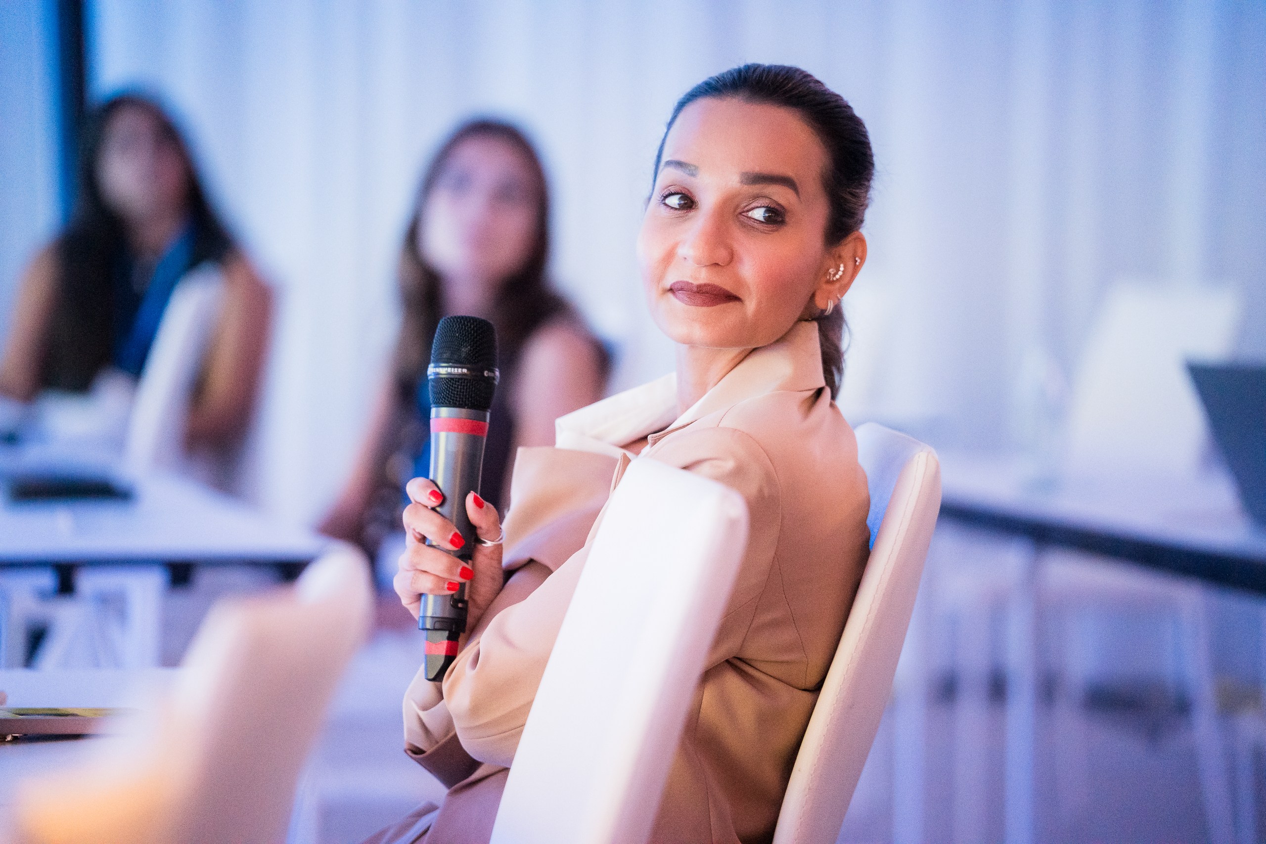 Conference attendee holding a microphone and looking to the side during a conference session.